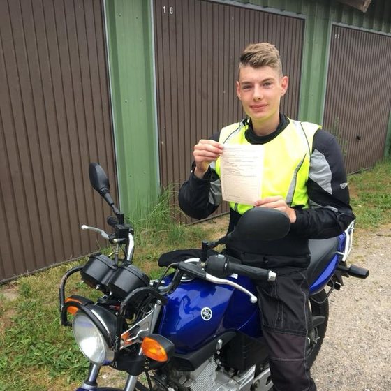 Fahrschüler mit Prüfbescheinigung vor dem Fahrschulwagen